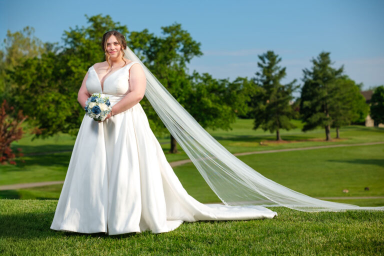 Maddie holding her bouquet with her veil trailing on the golf course at Heritage Hills